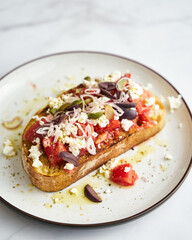 Dakos salad traditional Greek salad with soaked and crunchy barley rusks or bread, topped with juicy tomatoes, feta cheese, onions, olives, and a drizzle of olive oil. Popular apetizer
