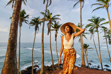 Young african female model posing in colorful clothes at tropical location at sunrise. Black woman...