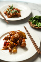 Chicken Manchurian on white plate with chopsticks. White marble background. Sweet and sour Chinese chicken recipe 