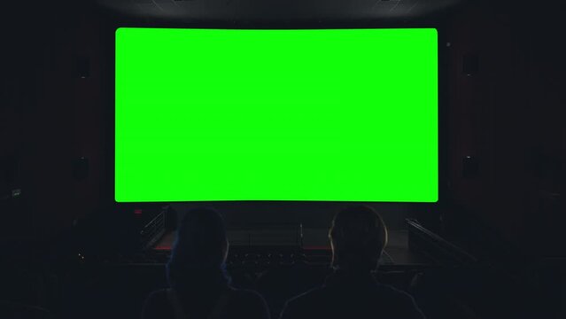 Couple Theater Green Screen Movie View Zoom In Cinema Dark Room. Couple inside a theater watching a green screen projection, zoom in cinema