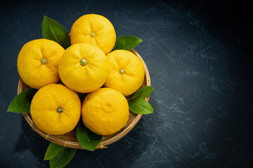 Fresh Sweet Yuzu Orange fruit in wooden basket over black background, Yuzu Orange fruit, Citron...