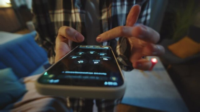 Close-up footage of unrecognizable female hands holding smartphone and ordering food delivery. Young woman in casual clothes using app, browsing, scrolling. Online shopping. Indoors