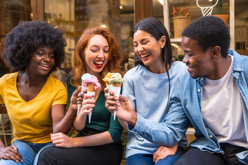 Multi-ethnic friends in an ice cream parlor sitting eating an ice cream, summer lifestyle having fun