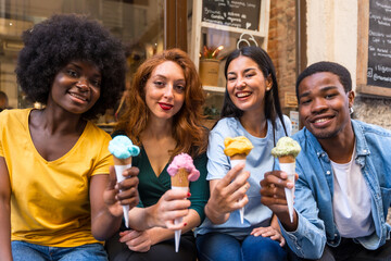 Multi-ethnic friends in an ice cream parlor eating an ice cream, summer fun, looking at camera