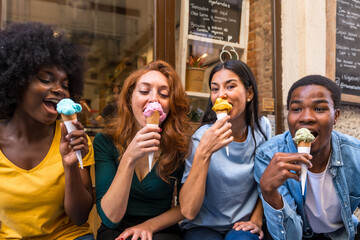 Multi-ethnic friends in an ice cream parlor eating ice cream, summer fun, sucking on ice cream from...