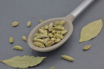 cardamom seeds onto a large spoon over dark slate