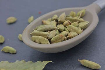 cardamom seeds onto a large spoon over dark slate