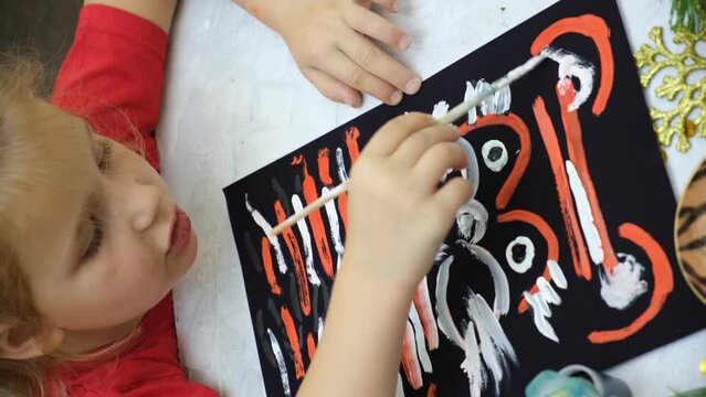 Child girl painting funny cat or tiger. DIY craft.