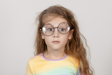 Fototapeta premium Portrait of a surprised little smart girl in glasses. Isolated on white background.