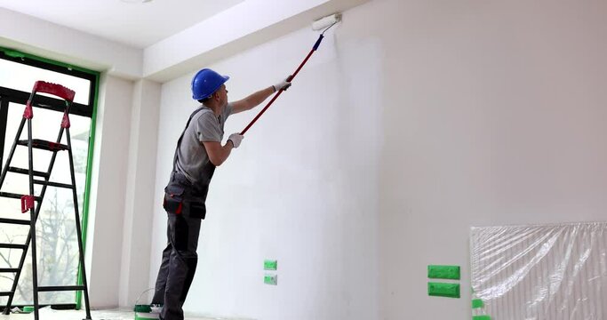 Painter painting wall with roller at construction site