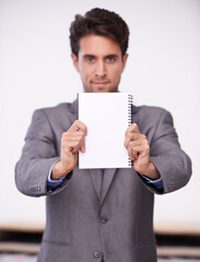 A message from the boss. A young businessman holding up a notepad.