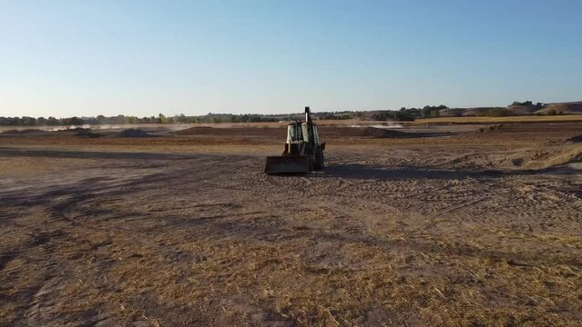 Drone video of a backhoe tractor in the desert.