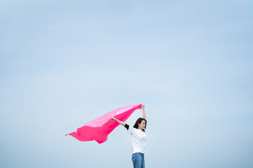 青空の中でピンクの布を持った女性