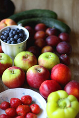 Berries in vintage porcelain dishes, other healthy fruit and vegetable on wooden table. Selective focus.
