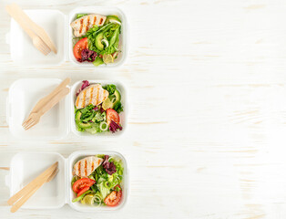 Food delivery of lunch boxes with salad on white wooden background. Copy space.