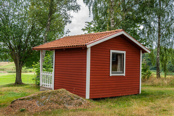 Fototapeta na wymiar Tiny little red wooden houses in Scandinavian Swedish style near a golf course. Vintage, cozy housing. Ideal place for introverts. 