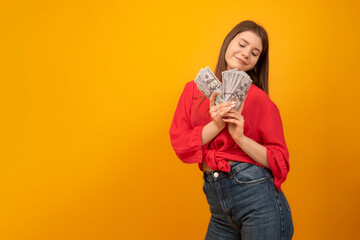 Teenage girl holds wad of U.S. dollars and smiles. Successful youth. Young business woman. Rich and carefree concept. Copy space.