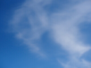 A defocussed picture of blue sky with white clouds suitable for a background