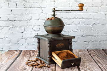 Antique coffee grinder with coffee beans and grinded, on rustic wooden table. Horizontal photograph...