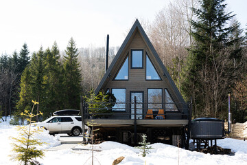 Wooden triangle country tiny cabin house with hot tub spa and suv car with roof rack in mountains....