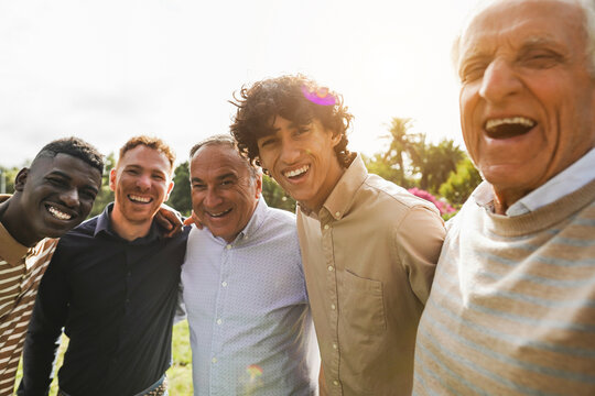 Multi generational men smiling in front of camera - Male multiracial group having fun togheter outdoor - Focus on rught boy face