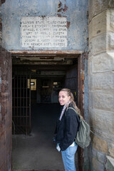 Obraz premium Smiling blonde young girl at the entrance gate of the Old Joliet Prison, she is visiting the old facilities