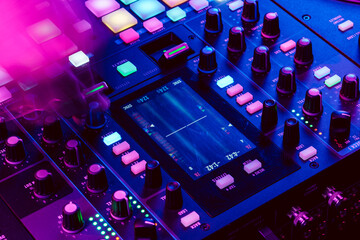 Close up of DJ mixing console in party light