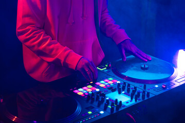 Hands of a DJ creating and regulating music on dj console mixer at club concert