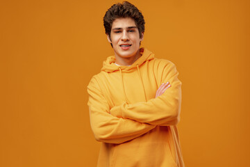 Portrait of a happy young casual man standing over yellow background