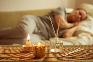 Scented candle, diffuser, sleeping woman in the background. The concept of relaxation, mental health