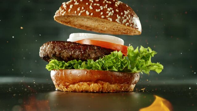 Super Slow Motion of Stacking Hamburger pieces. Camera in Motion. Filmed on High Speed Cinema Camera, 1000 fps. Placed on High Speed Cine Bot. Fire on foreground.