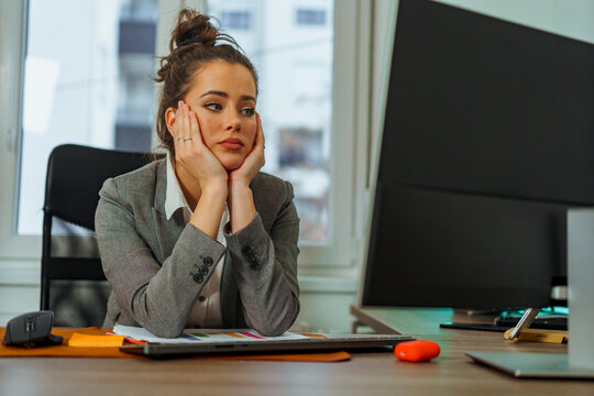Finance executive is tired and burned out, she's worried about her companies finance she's holding her head hand propped under her chin as she tries to think of a plan