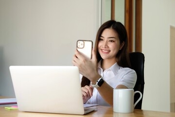 .Asia businesswoman using laptop talk to colleagues about plan in video call while smart working from home at living room..