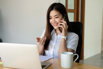 Asian business woman have the joy of talking on the phone, laptop and tablet on the office desk.