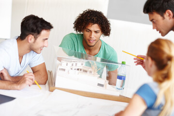 Looking over the design. A group of architects discussing a building model during a meeting.
