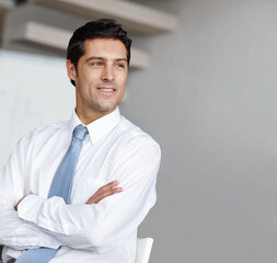 Coming up with ingenious business ideas. A handsome young businessman crossing his arms and looking...