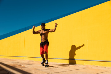 Black man on roller skates riding outside. Urban man posing with roller skates.