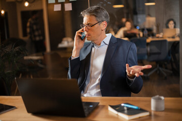  Businessman in office. Handsome man talking on phone at work.