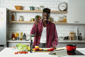  African man preparing food in modern kitchen. Handsome chef cooking pasta.