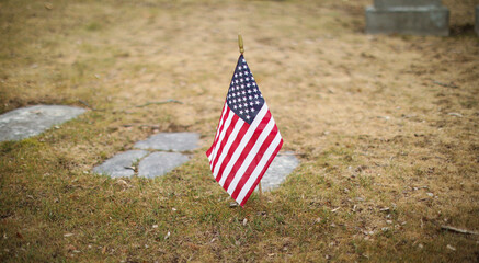 national american flag in war memorial of veteran soldiers in graveyard honoring their patriotic death by having fallen hero monument with US flag waving in background symbolizing fourth of july 