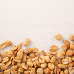 Spicy flavored peanut kernel spilling on white table background.