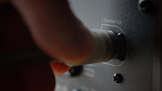 Close up shot of male hands connecting audio cable connector to sound speaker plug