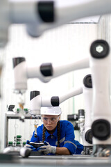 Robotic maintenance engineer working on robot arm connection and control using a remote control. Smart woman in industry 4.0 robotic engineering workshop in an electronic futuristic technology center