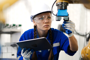Robotic maintenance engineer working on robot arm connection using tablet computer. Smart women...