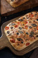 Focaccia with olive tomatoes and rosemary. Homemade Italian Sourdough Bread on white cafe table. - 581414142