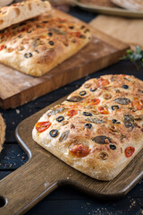 Focaccia with olive tomatoes and rosemary. Homemade Italian Sourdough Bread on white cafe table. - 581414149