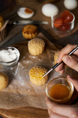 Chef hand making Mooncake a Chinese traditional pastry for Mid-Autumn festival. set on rustic wooden table. - 581414161