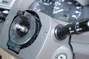 Steering column system. Closeup of repair or replacement steering wheel spiral cable clock spring instead of old broken one and selective focus.