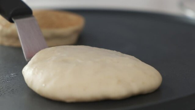 Slow motion flipping pancake with a spatula on hot pan.