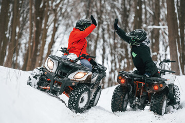 Making high five. Two people are riding ATV in the winter forest © standret